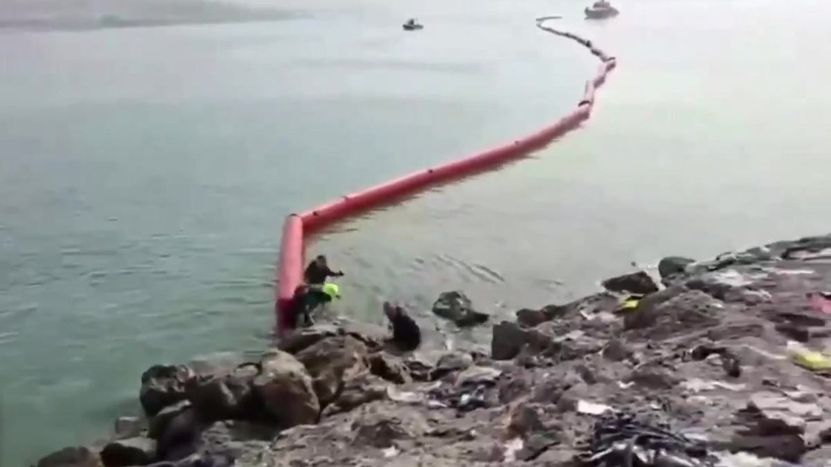 Barreira flutuante vermelha instalada pela Guarda Civil espanhola no mar, saindo das pedras do quebra-mar de Tarajal, em Ceuta